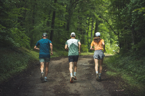 Deux hommes et une femme course à pied en forêt