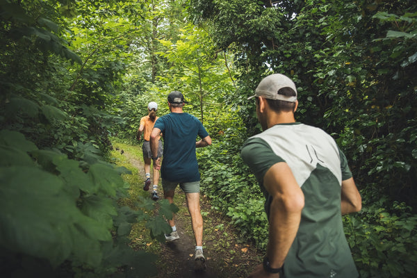 une femme et deux hommes course à pied en forêt